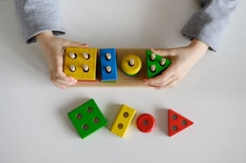 hands playing with a wooden block puzzle